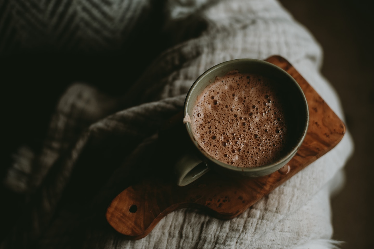 a cup of hot chocolate sitting on top of a wooden board