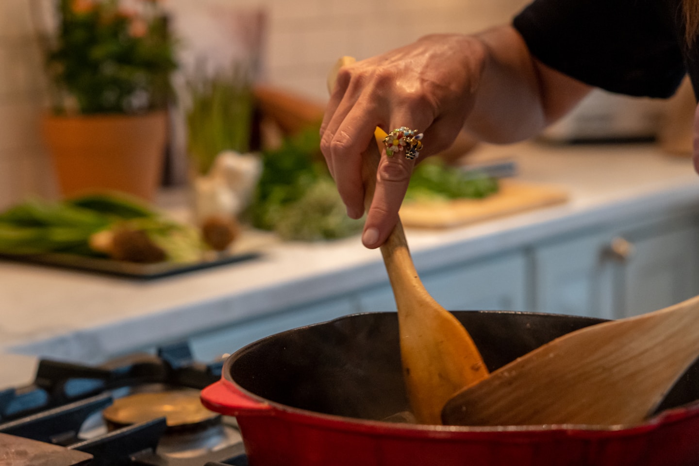 a woman stirring a pot with a wooden spoon